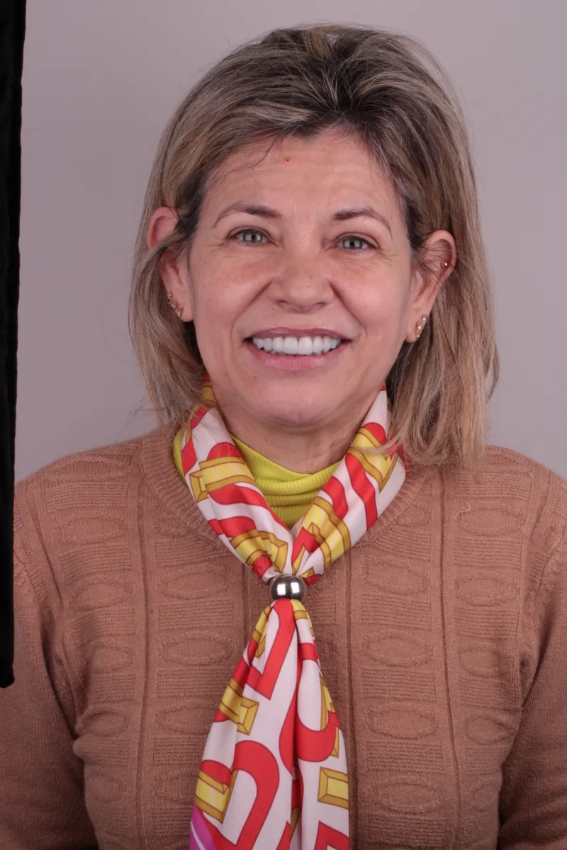 Mulher de cabelos curtos sorrindo, com blusa marrom e lenço estampado
