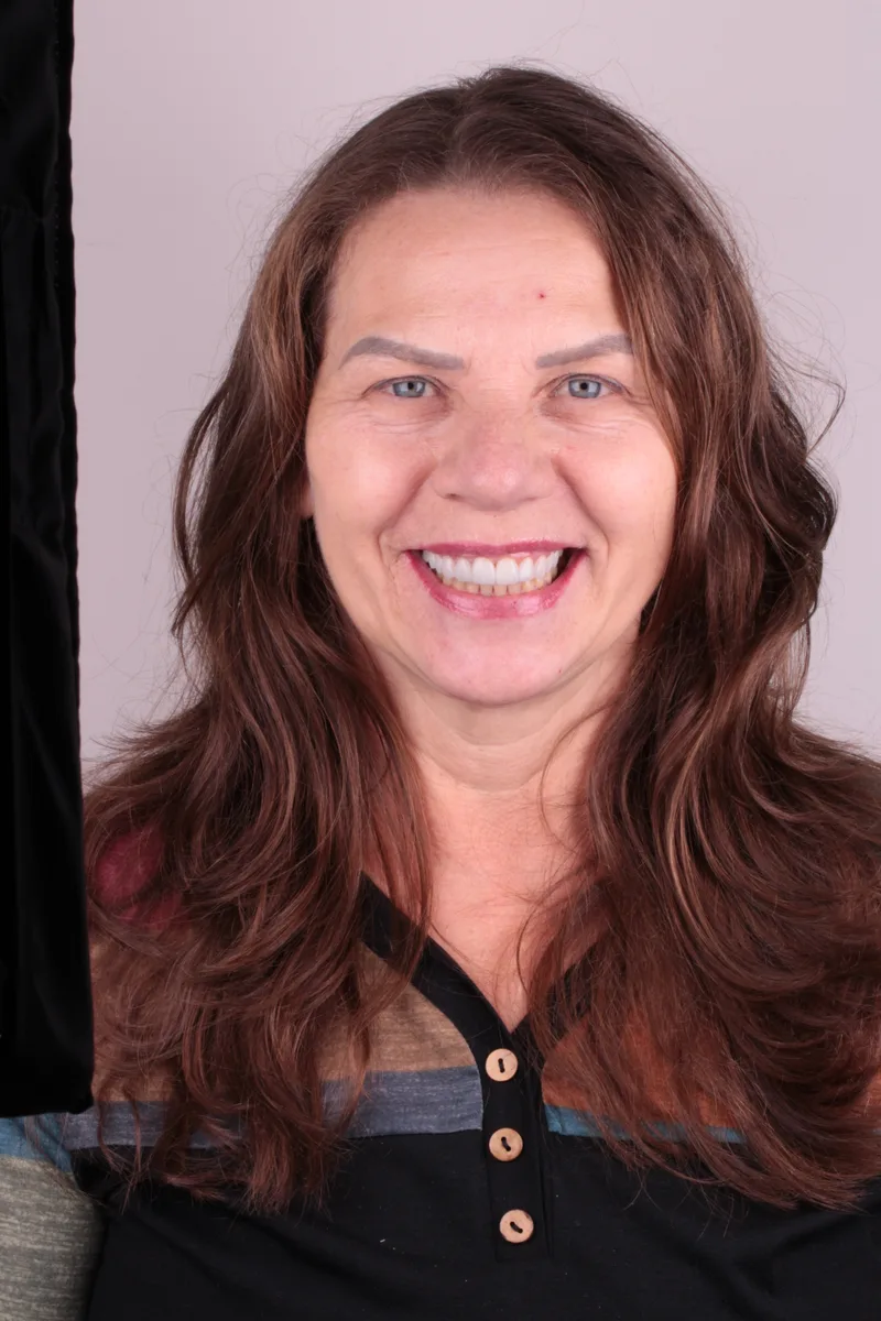 Mulher de cabelos castanhos longos sorrindo, com os dentes à mostra